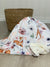 Babydecke liegt vor einem Körbchen. Motiv der  Decke sind kleinen Rehe und Blumen in Aquarelloptik. Farben der Decke sind helles orange/ grün, weiss und blau/grau Töne